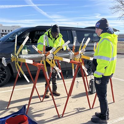 Two men stand with a large bullet-shaped tool with finds. The tool detects weaknesses in water pipes