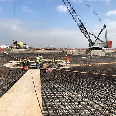 A construction site with people and cranes with concrete and steel mesh