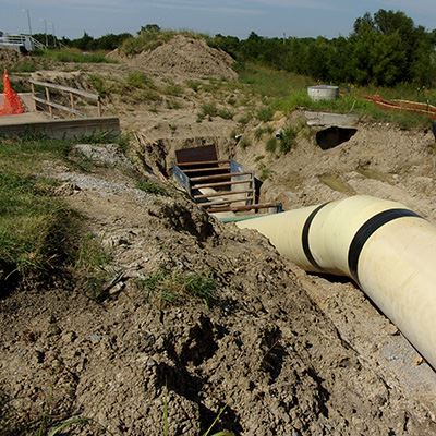 A large pipe goes into the ground at a construction site